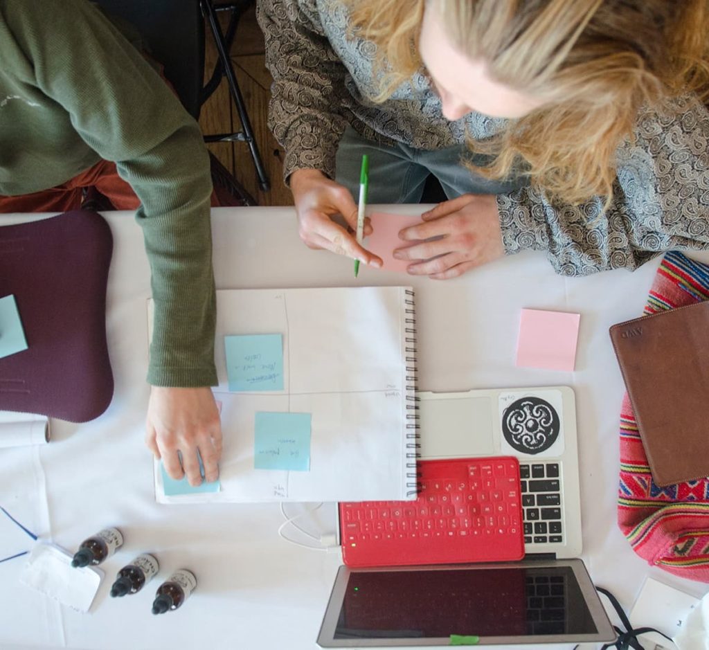 A group of women sitting around a table with a laptop and planning sheet