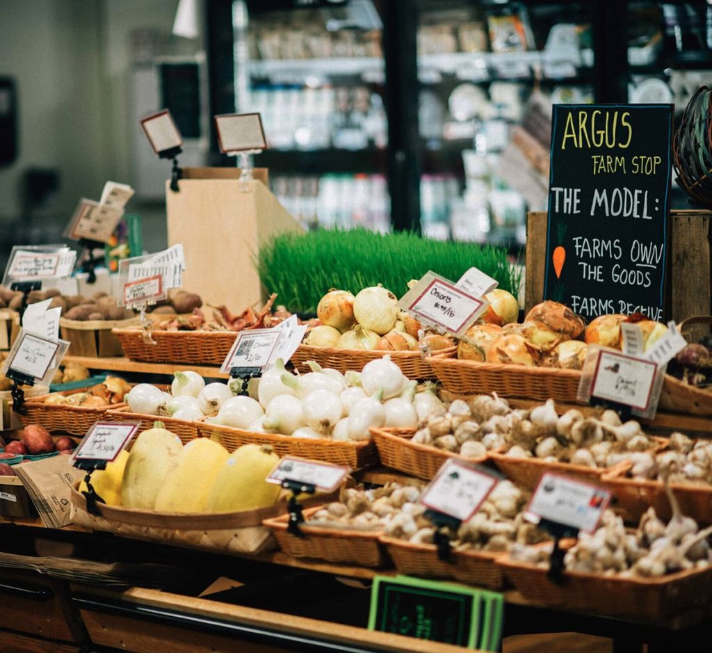 A grocery stand with local onions, garlic and squash