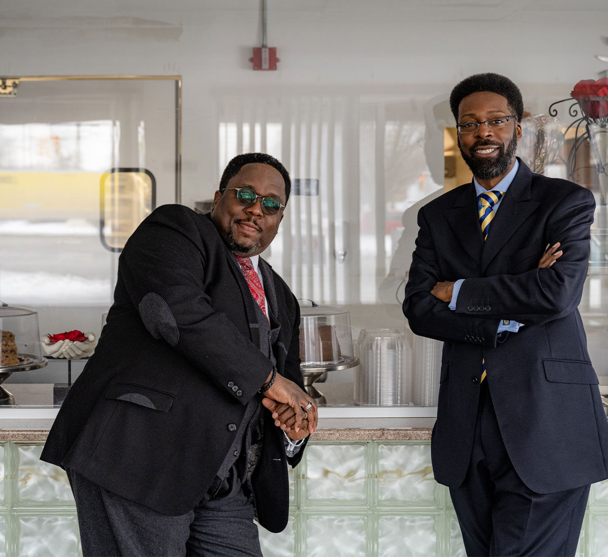 Two Black men in suits standing in a cafe