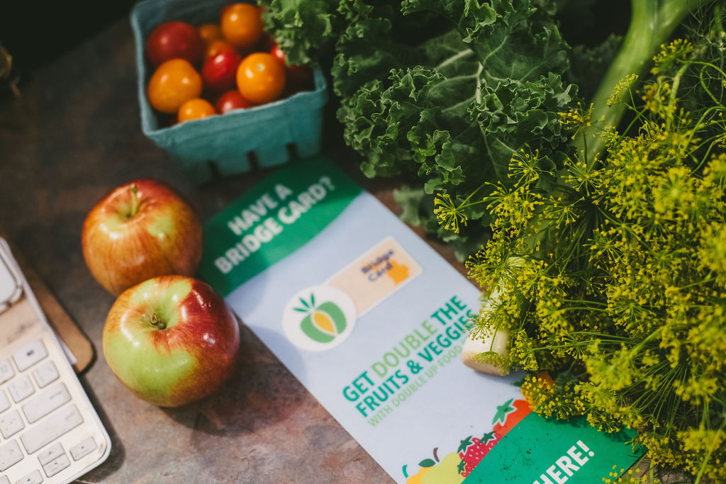 Apples, tomatoes, kale, and dill next to a flyer about doubling fruits and veggies with a Bridge Card.