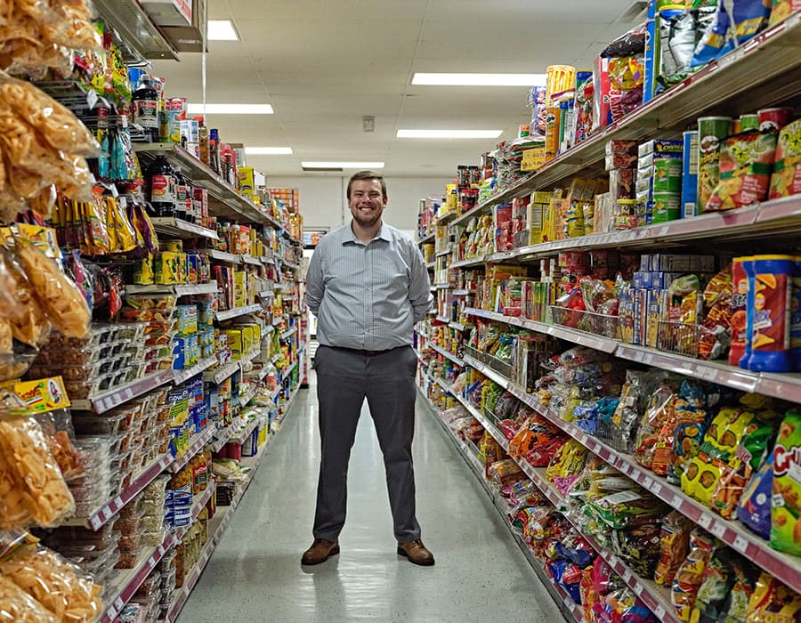 A smiling man standing in a grocery aisle