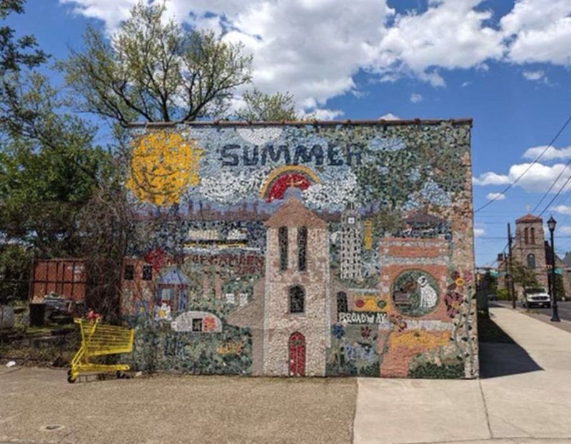A commnity mural make of small tiles in a parking lot with the word Summer
