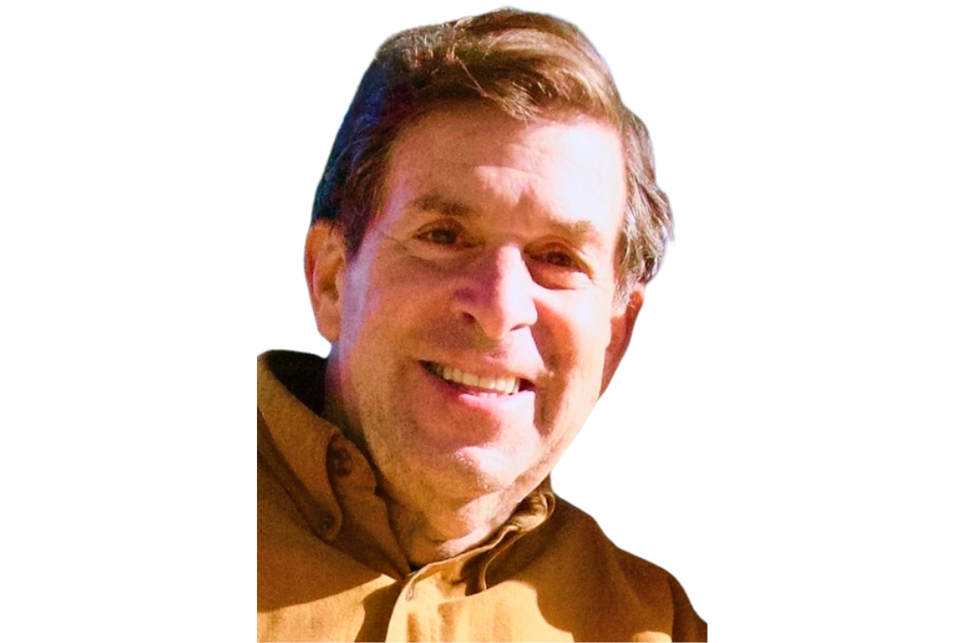 Smiling man with brown hair wearing a brown collared shirt, facing the camera against a white background.
