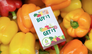 Yellow and orange bell peppers with a Buy $1 Get $1 promotional sign on top.