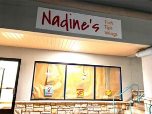 Storefront of Nadines, a restaurant offering fish, tips, and wings. Windows are covered with paper.