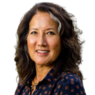 Smiling woman with wavy dark hair and a dark polka-dot blouse, pictured on a white background.