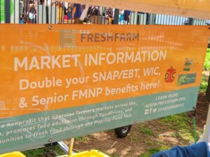 Orange FRESHFARM banner promoting doubling SNAP/EBT, WIC, and FMNP benefits at the farmers market.