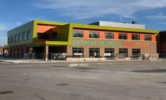 Newly constructed Detroit Peoples Food Co-op building with bright green and orange accents.